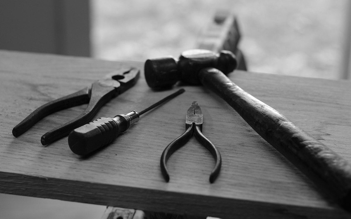 Hammer, pliers and hand tools laid out on a rustic wooden board - EQUIPE Egypt